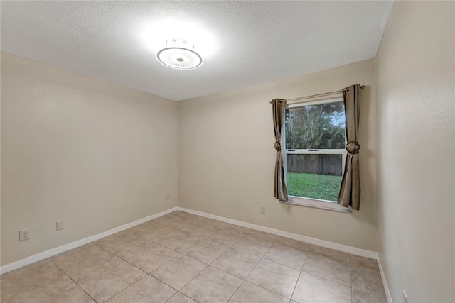 tiled empty room featuring a textured ceiling