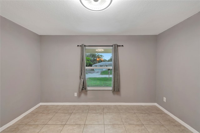 tiled spare room featuring a textured ceiling