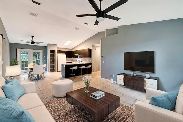 living room with a barn door, light tile patterned floors, sink, high vaulted ceiling, and ceiling fan