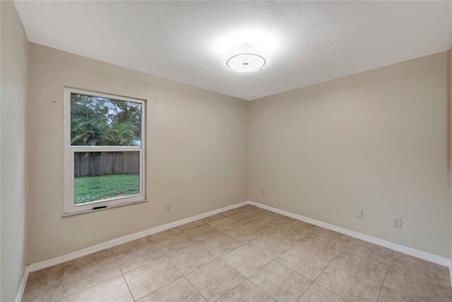 tiled empty room featuring a textured ceiling