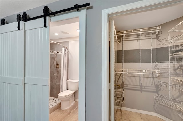 bathroom featuring curtained shower, tile patterned floors, and toilet