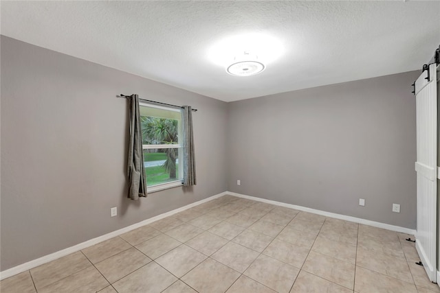 spare room featuring a textured ceiling, a barn door, and light tile patterned flooring