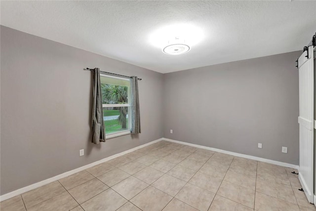 6245 6th Pl, Vero Beach, FL 32968 - spare room featuring a barn door, light tile patterned floors, and a textured ceiling