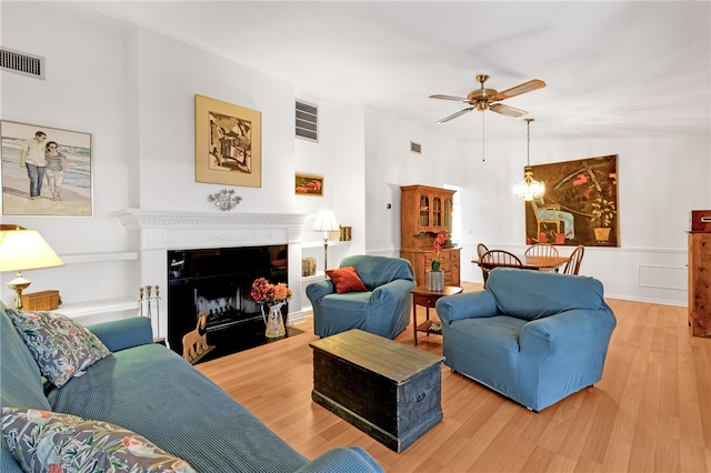 living room featuring ceiling fan with notable chandelier and wood-type flooring