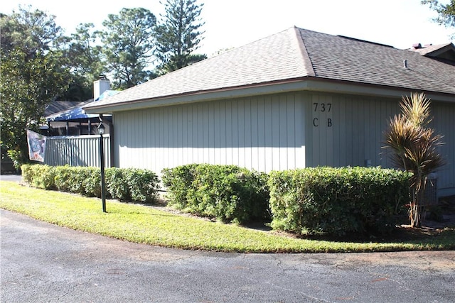 view of side of property with roof with shingles and a chimney