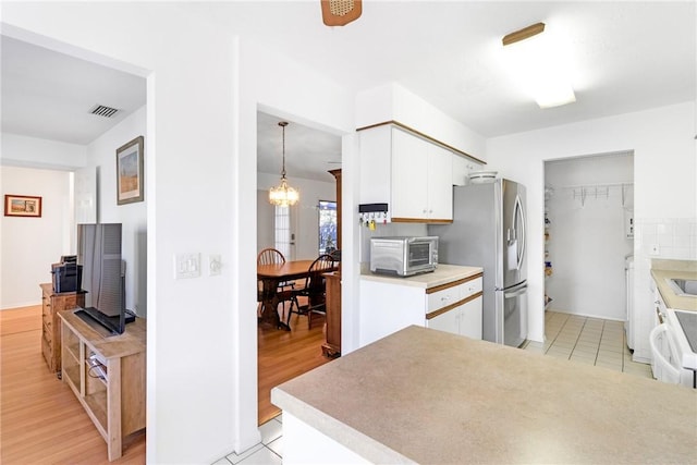 kitchen featuring stainless steel fridge, white cabinetry, a notable chandelier, and light wood-type flooring