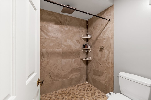 bathroom with a tile shower and toilet