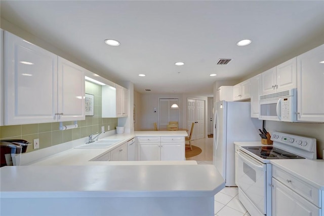 kitchen featuring white appliances, a sink, a peninsula, white cabinetry, and light countertops
