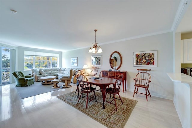 dining area featuring a chandelier, ornamental molding, light wood-style flooring, and baseboards