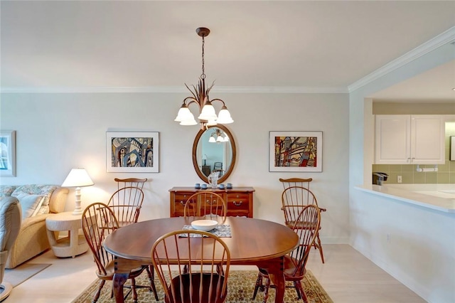 dining space featuring crown molding, a chandelier, baseboards, and light wood-style flooring