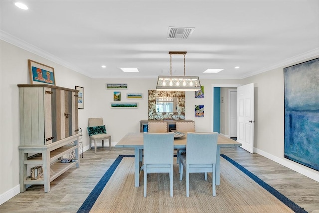 dining area featuring light wood-style floors, visible vents, and crown molding