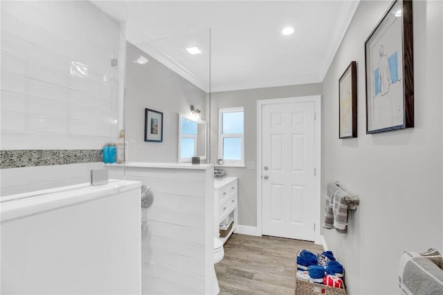 bathroom with wood finished floors, vanity, baseboards, ornamental molding, and walk in shower