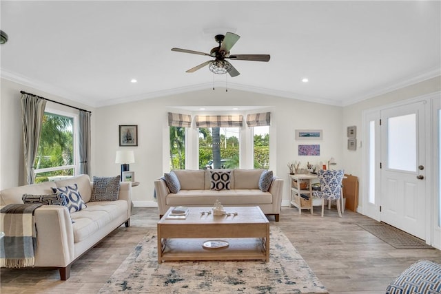 living room with lofted ceiling, light wood-style flooring, a ceiling fan, baseboards, and ornamental molding