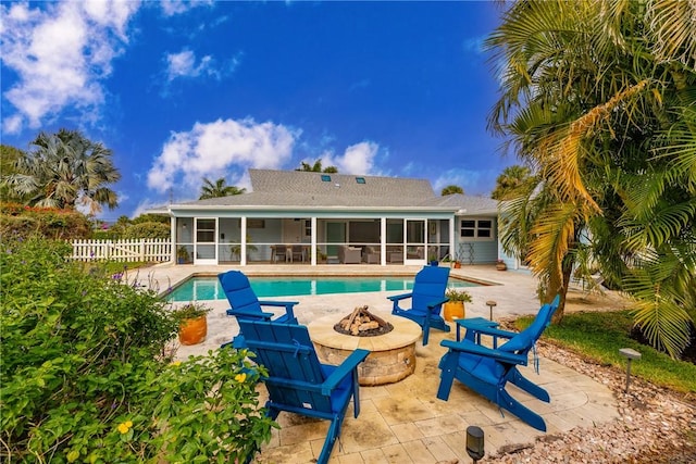 exterior space featuring an outdoor fire pit, a patio area, fence, and a sunroom