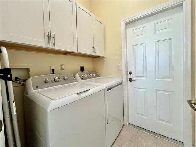 washroom featuring cabinets, light tile patterned floors, and washing machine and dryer