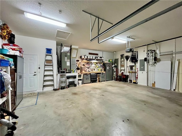 garage featuring a workshop area, electric panel, and a garage door opener