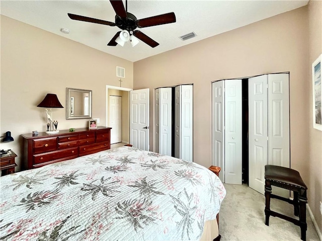 carpeted bedroom featuring ceiling fan and two closets