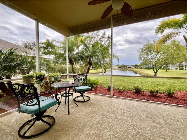 sunroom featuring ceiling fan and a water view