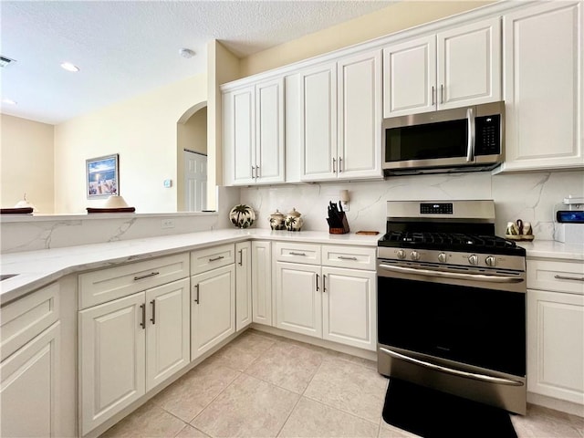 kitchen featuring light tile patterned flooring, white cabinetry, appliances with stainless steel finishes, and tasteful backsplash