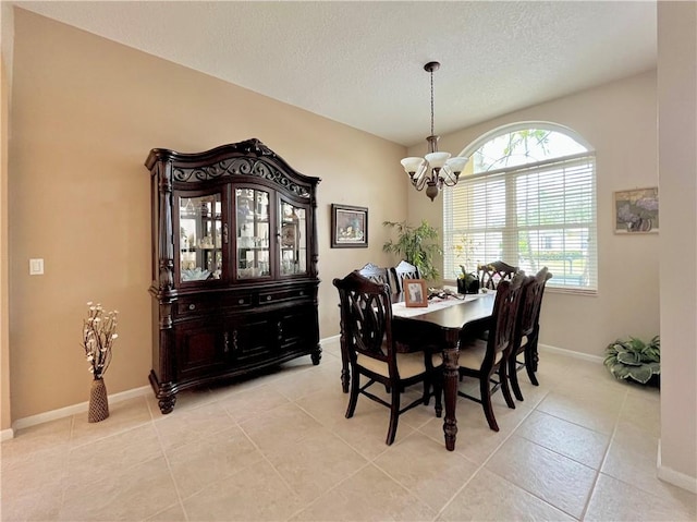 tiled dining area with a textured ceiling and a chandelier