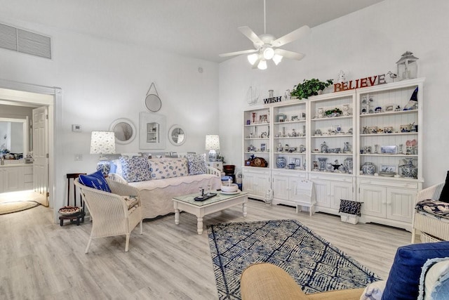 living room with light hardwood / wood-style flooring, a high ceiling, and ceiling fan