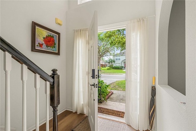 entrance foyer with arched walkways, wood finished floors, and stairs