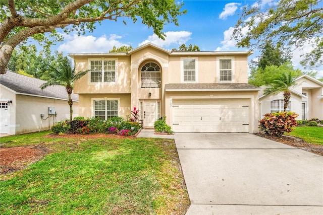 view of front of property featuring a garage, driveway, a front yard, and stucco siding