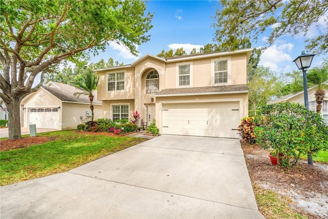 traditional-style home with stucco siding, concrete driveway, a garage, and a front yard