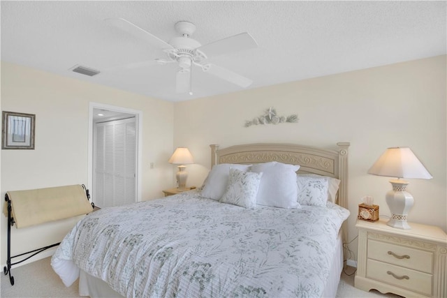 bedroom featuring a textured ceiling, ceiling fan, light carpet, and a closet