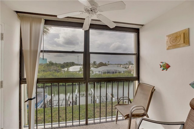 sunroom / solarium featuring a water view and ceiling fan