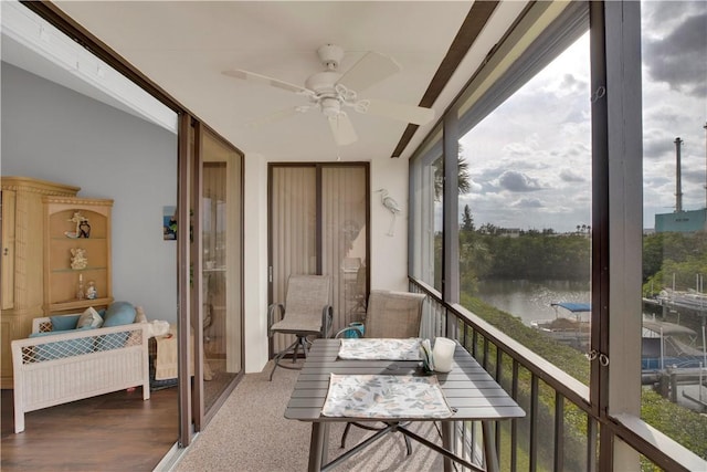 sunroom featuring plenty of natural light, ceiling fan, and a water view