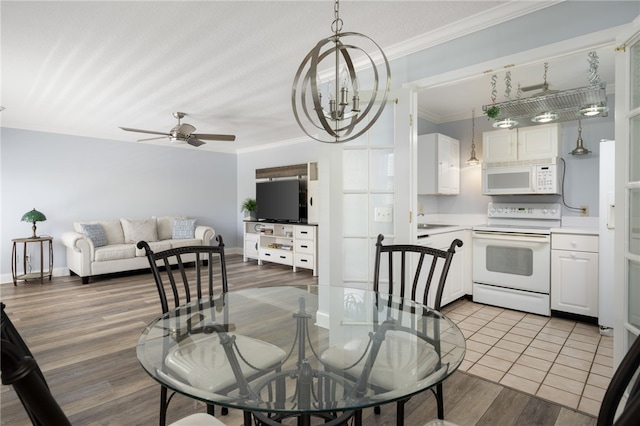 dining area featuring crown molding, ceiling fan with notable chandelier, and wood finished floors