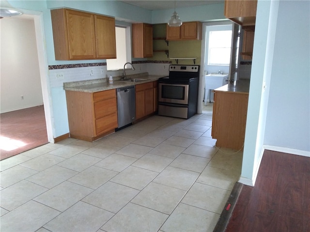 kitchen featuring sink, hanging light fixtures, backsplash, light tile patterned floors, and appliances with stainless steel finishes