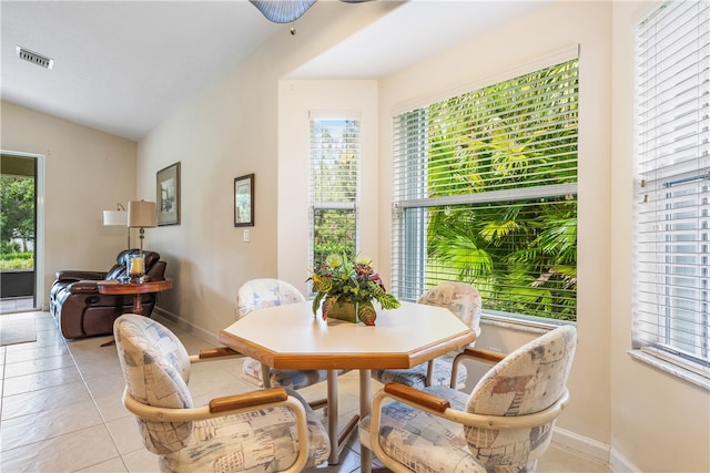 dining space with a wealth of natural light, light tile patterned floors, and vaulted ceiling