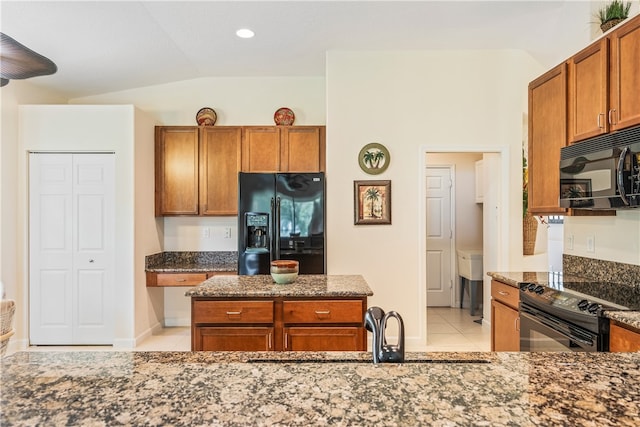 kitchen featuring sink, dark stone countertops, vaulted ceiling, light tile patterned floors, and black appliances