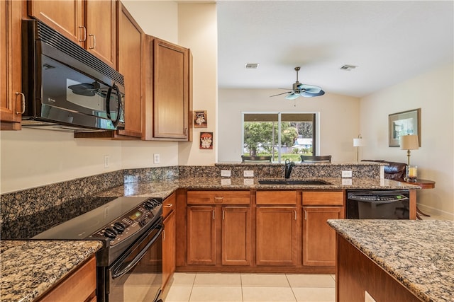 kitchen with stone counters, black appliances, sink, light tile patterned floors, and kitchen peninsula