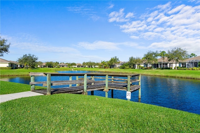 view of dock with a lawn and a water view