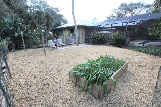 back of property featuring glass enclosure, a garden, a patio area, and a chimney