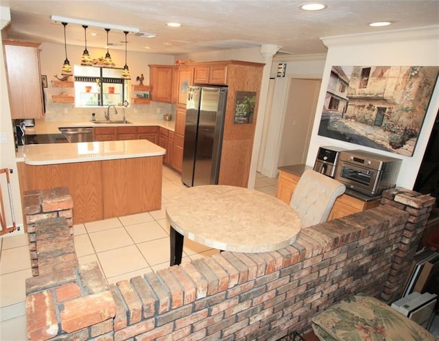 kitchen featuring light tile patterned floors, tasteful backsplash, appliances with stainless steel finishes, a sink, and a peninsula