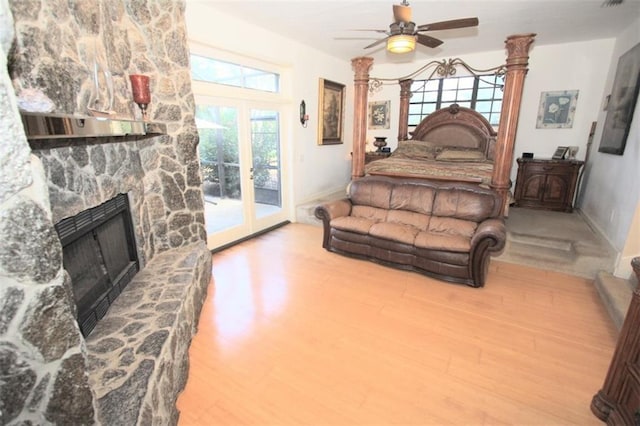 bedroom with access to exterior, a fireplace, a ceiling fan, wood finished floors, and baseboards