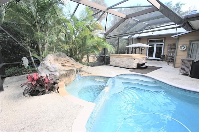 pool with a patio, french doors, glass enclosure, and a hot tub