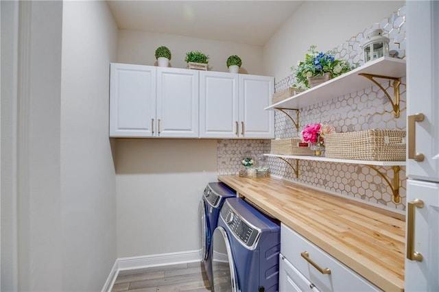 washroom featuring cabinets, washing machine and dryer, and light hardwood / wood-style floors