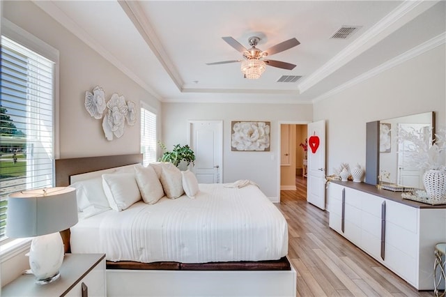 bedroom featuring light hardwood / wood-style flooring, a raised ceiling, ceiling fan, and crown molding