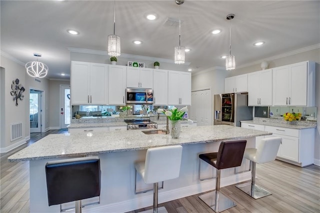 kitchen featuring white cabinetry, a spacious island, decorative light fixtures, a kitchen bar, and appliances with stainless steel finishes