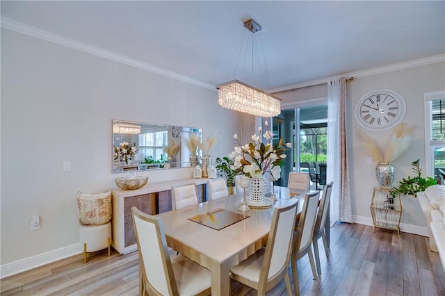 dining space with a notable chandelier, light hardwood / wood-style floors, and ornamental molding