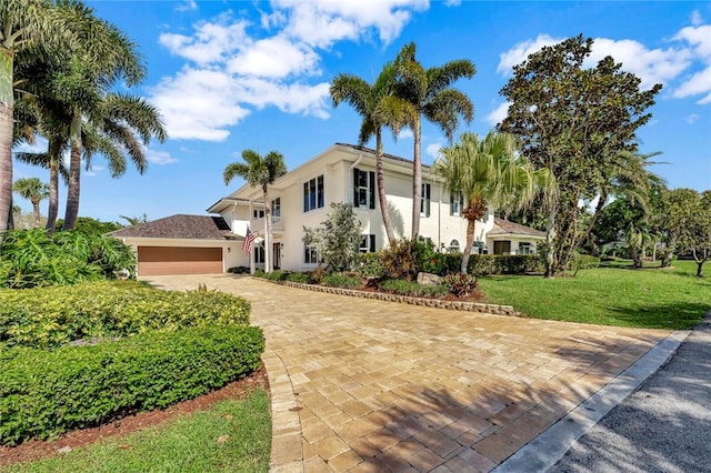 view of front of property with stucco siding, decorative driveway, and a front yard