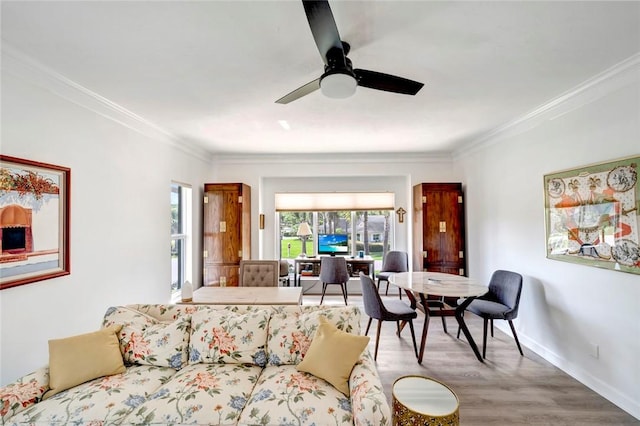 living room with wood finished floors, a ceiling fan, baseboards, and ornamental molding