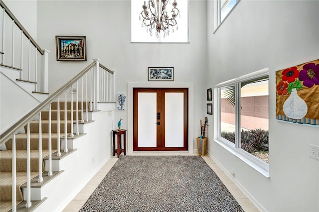 foyer entrance with light tile patterned floors, french doors, a towering ceiling, and a healthy amount of sunlight