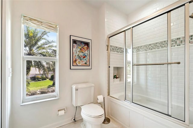 bathroom with toilet and bath / shower combo with glass door