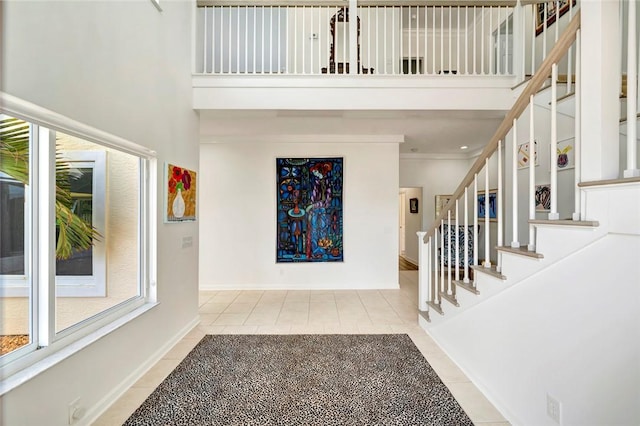 foyer entrance featuring light tile patterned floors, stairs, a high ceiling, and baseboards